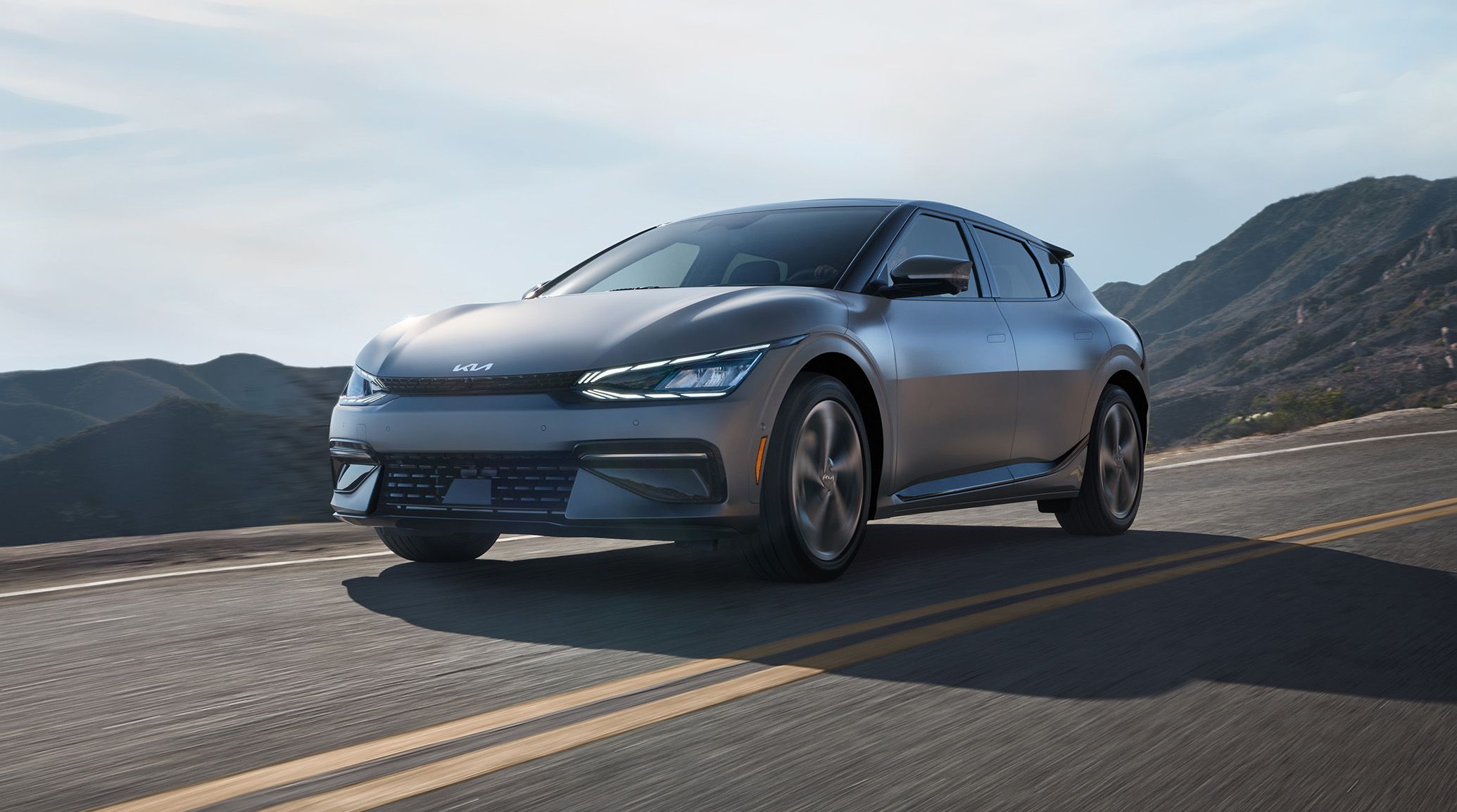 2024 Kia EV6 In Steel Gray Driving On An Elevated Highway Through The Mountains Three-Quarter View